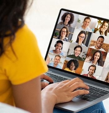 a person sitting in front of a laptop computer with a group of people on the screen
